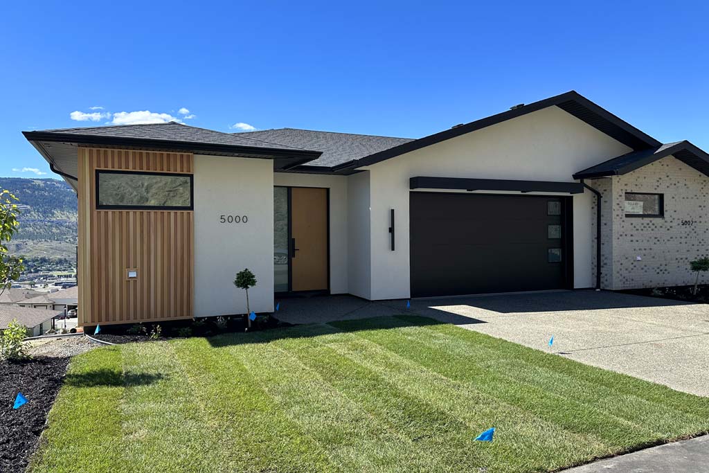 Exterior of a modern single-family home with wood accents, attached garage, and mountain views