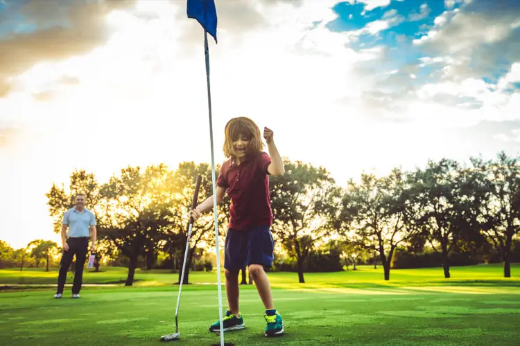 Child playing golf with father
